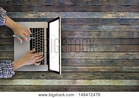 man's hands typing on a laptop that is on a wooden desk with copy space.
