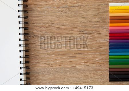 color pencils with notebook non wooden table