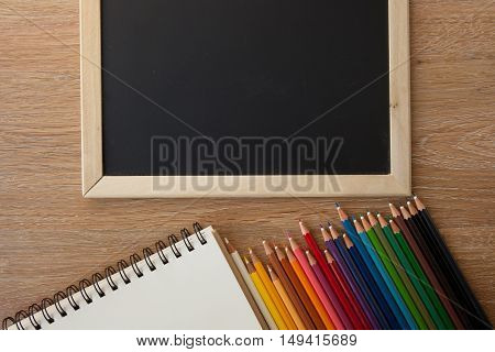 color pencils with notebook and a blackborad