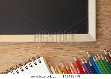 color pencils with notebook and a blackborad