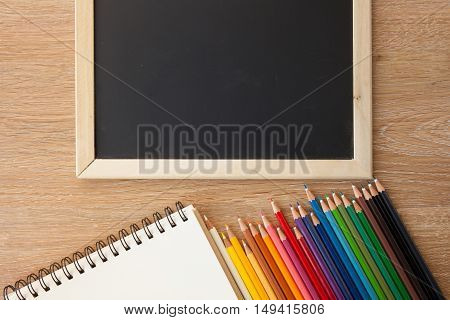 color pencils with notebook and a blackborad
