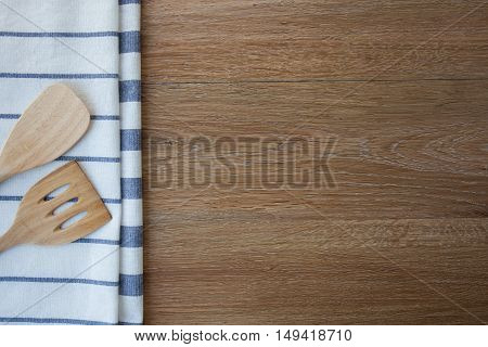 Wooden kitchen utensils and linen kitchen towels on dark wood tabletop with copy space in the center