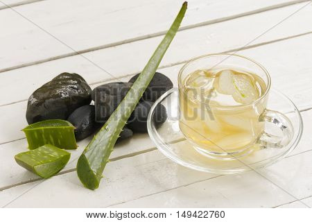 Aloe Vera Herbal and Aloe Vera  juice and slice on plate with black rock on wooden white background.Top view and close up.001