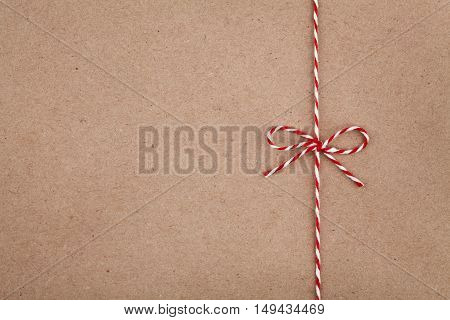 Christmas or New Year string or twine tied in a bow on kraft paper texture. Gift or present concept.