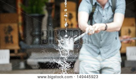 Foreign tourist takes water for purification at the entrance of Japanese temple