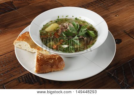 Chorba - traditional middle eastern soup in a white plate. Wooden background.