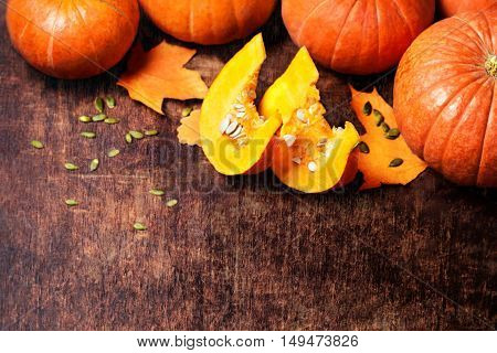 Autumn Pumpkin Thanksgiving Background - orange pumpkins with cut pieces over wooden table