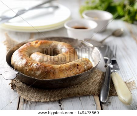 fragrant juicy homemade sausages in a pan, fork on a napkin