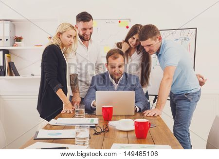 Happy business team, work result. People laugh near laptop in the office. Successful corporate group of female and male coworkers look at corporate internet site together at work