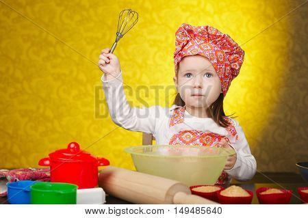 Little baker or cook girl cuts dough for cookies on kitchen with form