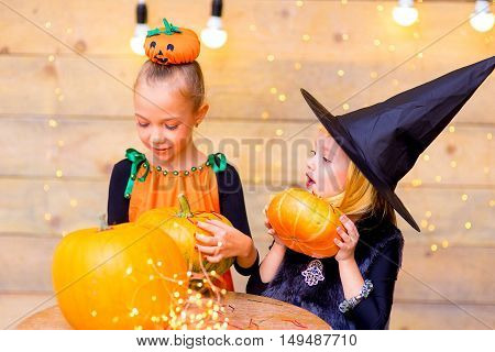 Happy group of children during Halloween party playing around the table with pumpkins
