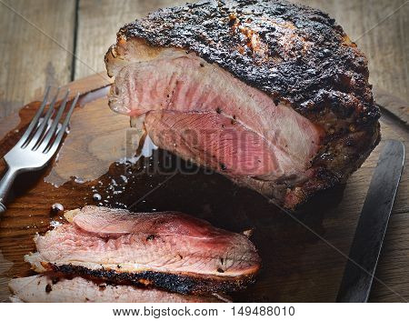 juicy piece of pork, pepper, noh and fork on a wooden background