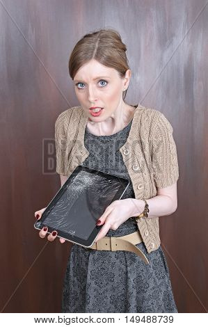 Young woman with shocked face expression over broken tablet display