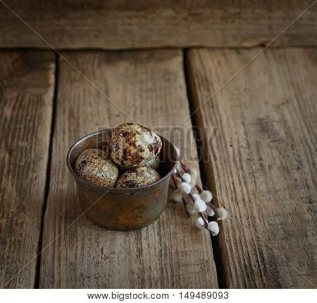 quail eggs and willow twigs on a wooden background