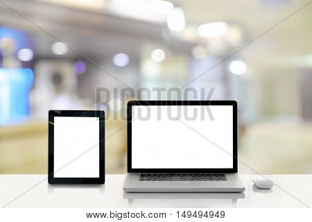blank screen laptop and tablet on wooden table with blur hospital background.