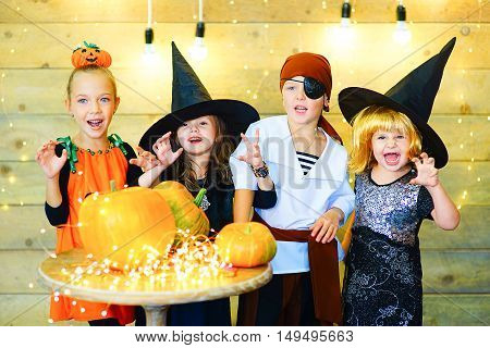 Happy group of witch children pirate and demons during Halloween party playing around the table with pumpkins