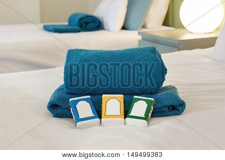 Hotel room bed with towels and soap bars with customizable labels