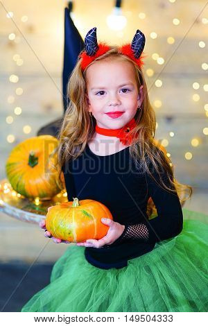 Happy deamon children during Halloween party playing around the table with pumpkins