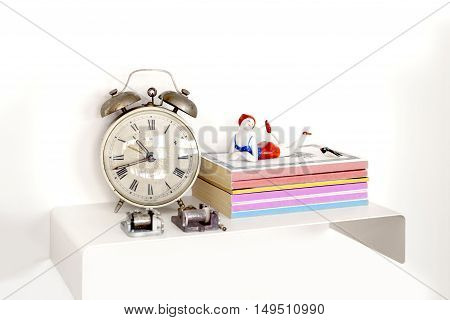 Alarm clock and books on nightstand on a bright lit room