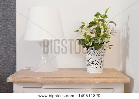 Nightstand with lamp and plant on a bright room