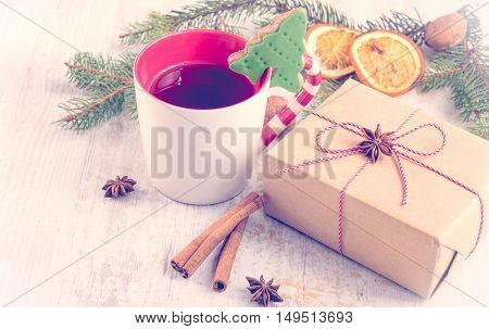 Homemade butter nuts christmas tree shaped cookie with icing pine orange slicescinnamon anise and walnuts over white wood background. A cup of berry tea and a gift box wrapped in kraft paper. Christmas decoration.