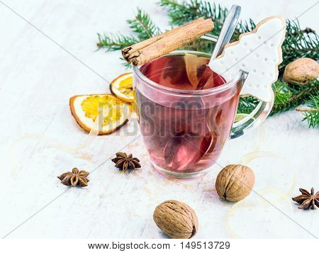Homemade butter nuts christmas tree shaped cookie with icing pine orange slicescinnamon anise walnuts and golden ribbon over white wood background. A cup of berry tea. Christmas decoration.