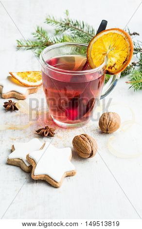 Homemade butter nuts star shaped cookies with icing pine orange slicescinnamon anise walnuts and golden ribbon over white wood background. A cup of berry tea. Christmas decoration.