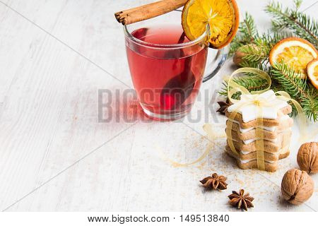 Homemade butter nuts star shaped cookies with icing pine orange slicescinnamon anise walnuts and golden ribbon over white wood background. A cup of berry tea. Christmas decoration.
