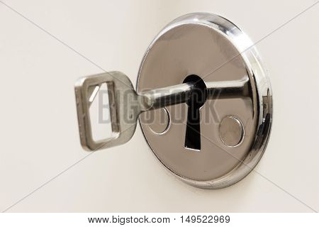 The key is inserted into the keyhole on a white background closeup