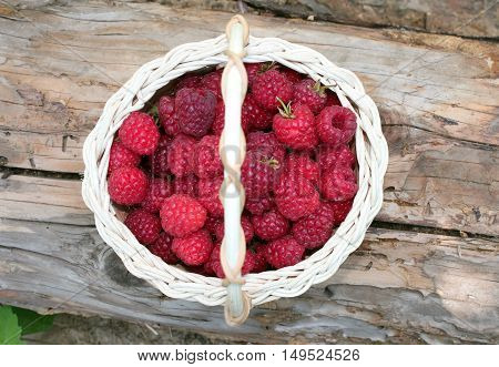 Raspberries in basket on wooden background top view