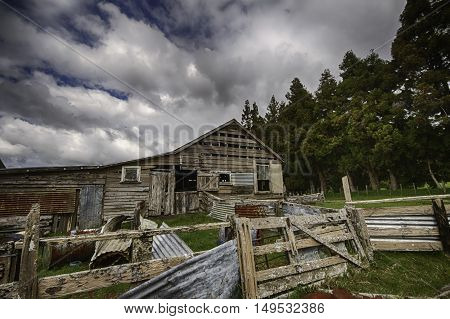 Old dilapidated shearing shed against a dynamic cloudy blue sky background