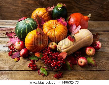 Abundant harvest concept with pumpkins apples and berries. Thanksgiving background with seasonal vegetables and fruits. Fall background.