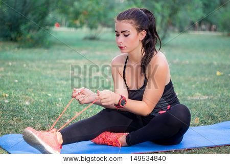 Young fitness girl ties bootlaces for training workout outdoor