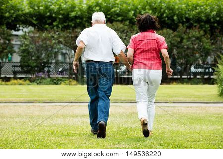 Rear View Of Senior Couple Running Together In Park