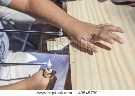 Children learning to work with marquetry saw. Closeup