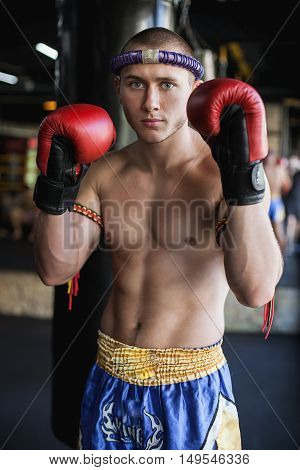 Kickbox or muay thai fighter standing with hands on gloves on gym