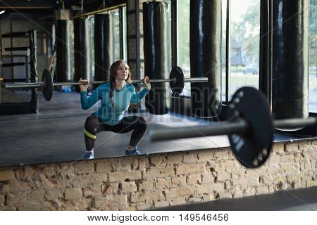 Muscular woman in a gym doing heavy weight exercises. Young woman doing weight lifting at health club.