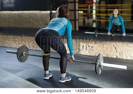 Muscular woman in a gym doing heavy weight exercises. Young woman doing weight lifting at health club.