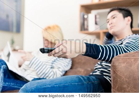 Estranged Asian couple reading and watching tv