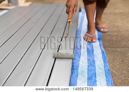 Worker painting steel bars with paintroller on construction site