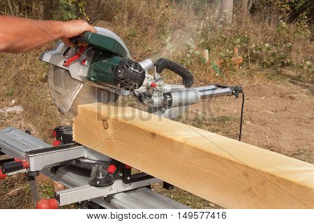 Construction Worker Cutting Beam with saw. Workers cutting timber wood with chainsaw. Saw sawing timber.