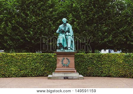 Copenhagen, Denmark - September, 22th, 2015. Hans Christian Andersen statue in Rosenborg garden. Bronze sculpture of famous danish fairy tale writer amid green plants.