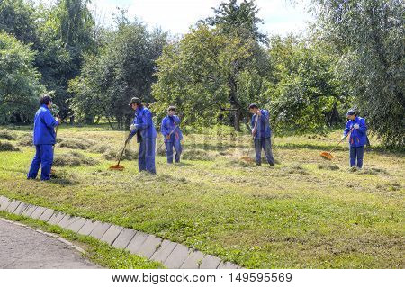 MOSCOW RUSSIA - August 18.2013: Migrant workers clean grass clippingson the lawn in the park Kolomenskoye