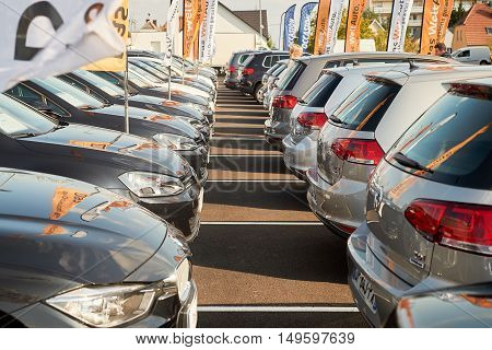 PARIS FRANCE - OCT 10 2015: Mature woman walking between rows of new car to choose the most precious one at the Volkswagen and BMW store car automotive