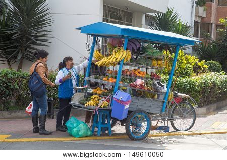 Lima, Peru - September 17, 2015: A lady selling fruit to customers on the street with her fruit bicycle
