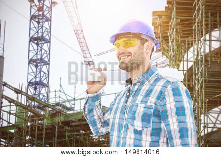 Smiling architect looking away while holding blueprint against work in progress in the city