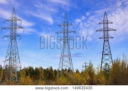 High-voltage electric lines and electric poles in the field in the fall