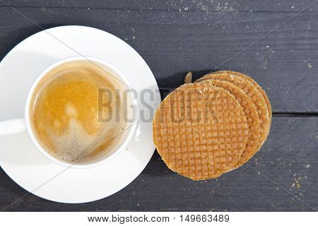 Dutch cookie stroopwafels with cup of coffee on black wooden background