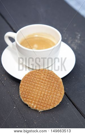 Dutch cookie stroopwafels with cup of coffee on black wooden background