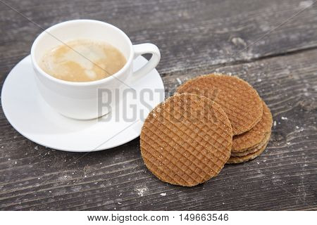 Dutch cookie stroopwafels with cup of coffee on brown wooden background